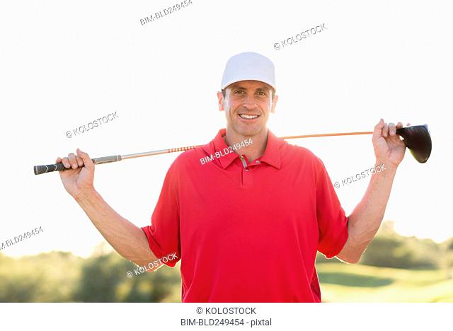 Portrait of Hispanic golfer holding golf club on shoulders