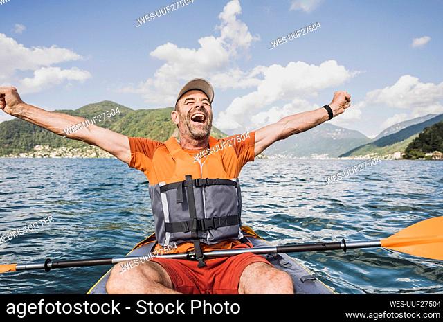 Excited mature man screaming with arms outstretched on lake