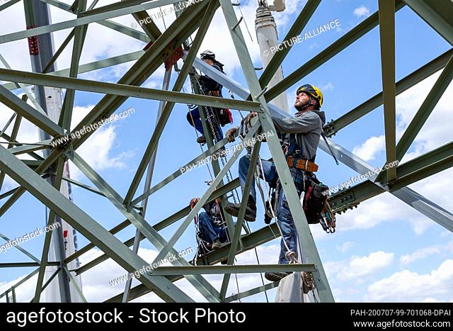 06 July 2020, Saxony, Heidenau: Technician Roman Beu (right) climbs up the power pylon to his workplace. In Heidenau near Dresden in Saxony