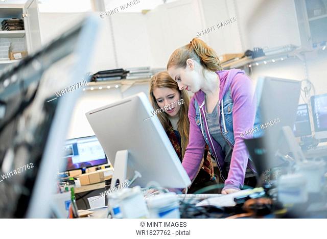 Computer Repair Shop. Two women working together leaning ou a counter