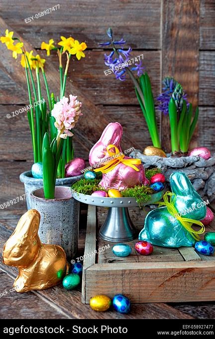 Bunte Schokohasen und Blumen fuer Ostern