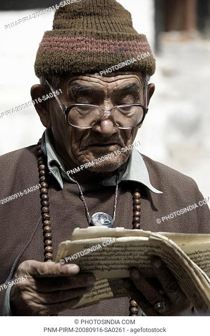 Senior man reading Buddhist scriptures in a monastery, Likir Monastery, Ladakh, Jammu and Kashmir, India