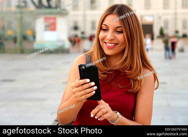 Latin American smiling woman walking in the street paying online for e-commerce on her mobile phone
