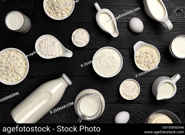 Different types of dairy products on black wooden background, set of milk, cottage cheese, sour cream and yogurt, top view