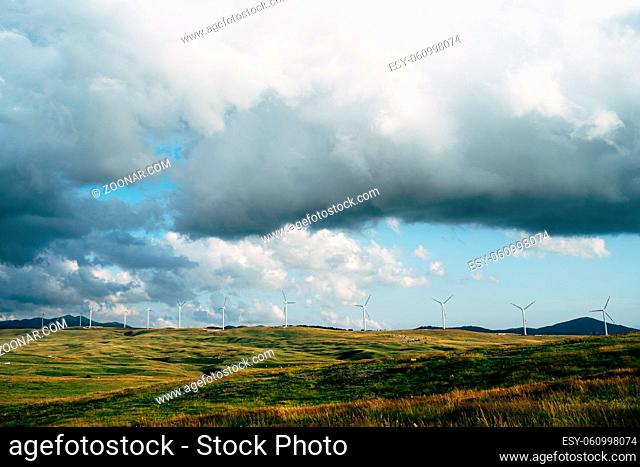 Panorama of many huge wind turbines on the horizon line with blue sky with clouds. Green technology concept. Industrial wind farm in northern Montenegro