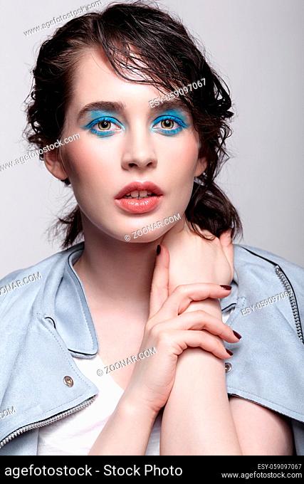 Portrait of female in blue jacket. Woman with unusual beauty makeup and wet hair. Girl with perfect skin, green pistachio colour eyes and blue shadows make-up