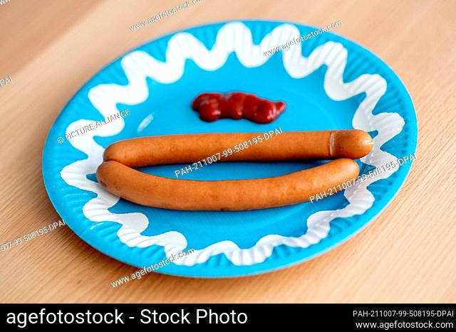 ILLUSTRATION - 01 October 2021, Lower Saxony, Oldenburg: A paper plate with two bockwursts and ketchup stands on a table
