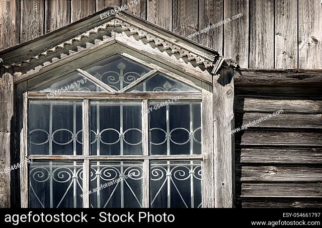 A fragment of the window of the ancient Orthodox wooden Church with wrought iron bars and carved wooden platbands