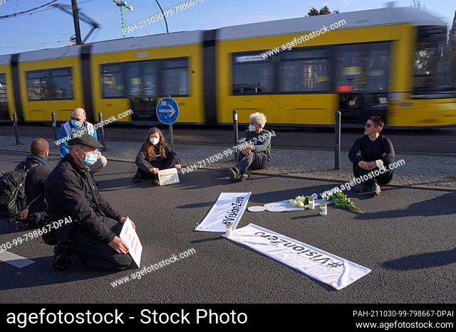 30 October 2021, Berlin: At a vigil for killed pedestrians, some participants sit on Landsberger Allee at the height of Fritz-Riedel-Straße and Hausburgstraße