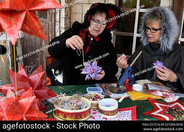 16 December 2023, Saxony, Schkeuditz: Bärbel Nickau (l) and Susanne Lang make various stars as tree decorations at the Victorian Christmas market at...