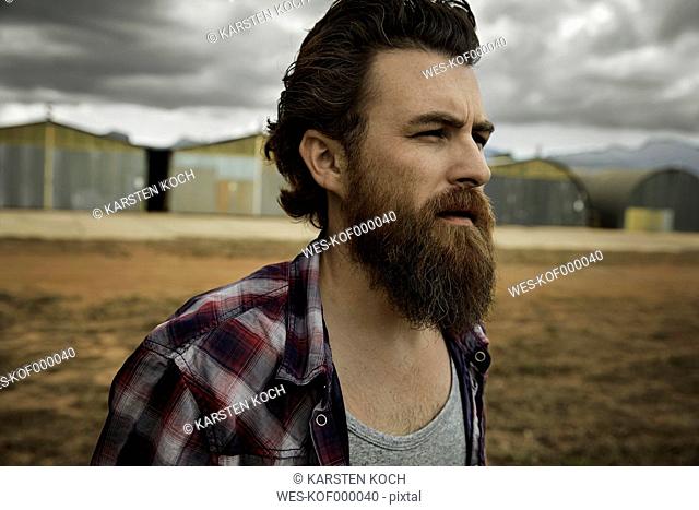 Serious man with full beard in abandoned landscape
