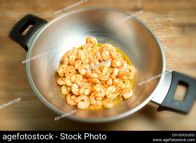 Shrimp in wok pan on wooden top background