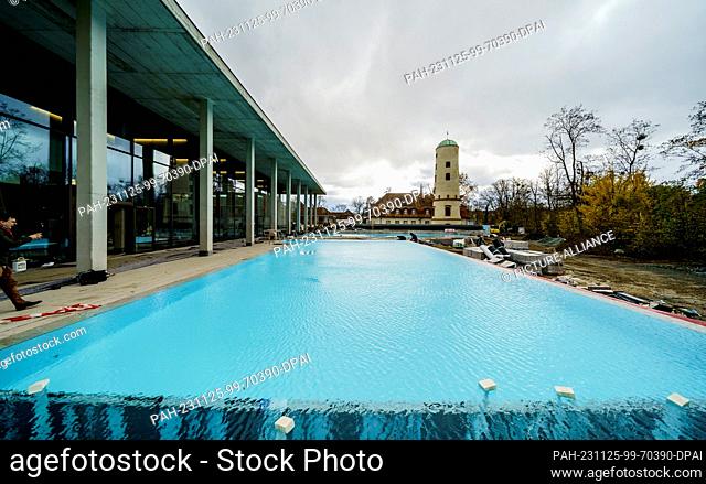 PRODUCTION - 24 November 2023, Hesse, Bad Nauheim: The outdoor pool is filled with water for the leak test. The historic ""Waitz Tower"" and the ""Balneological...