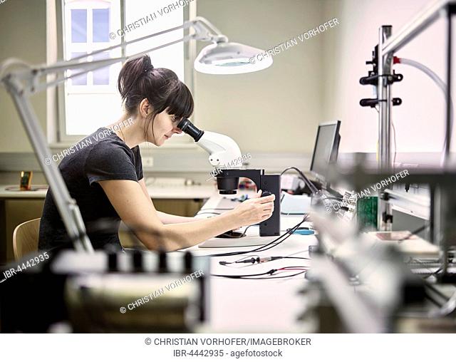 Technician, young woman using electronic microscope