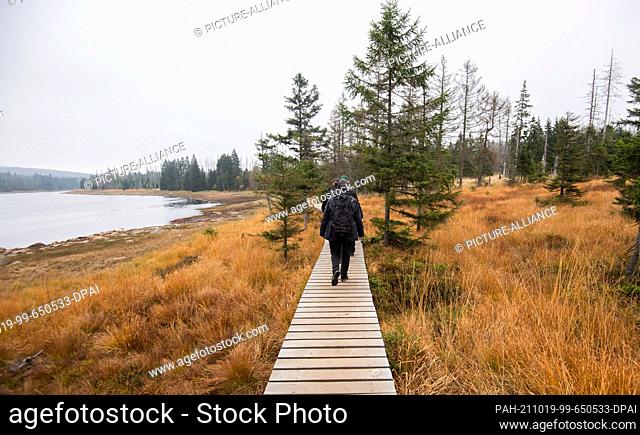 19 October 2021, Lower Saxony, Oderteich: Hikers walk on a footbridge at the Oderteich dam in the Harz National Park. Photo: Julian Stratenschulte/dpa