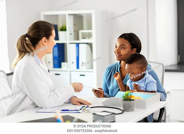 happy mother with baby son and doctor at clinic