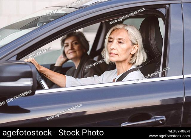 Businesswoman sitting with colleague driving car in city