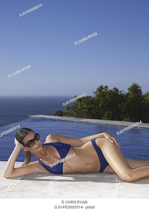 Woman in bikini and sunglasses relaxing outdoors with blue sky