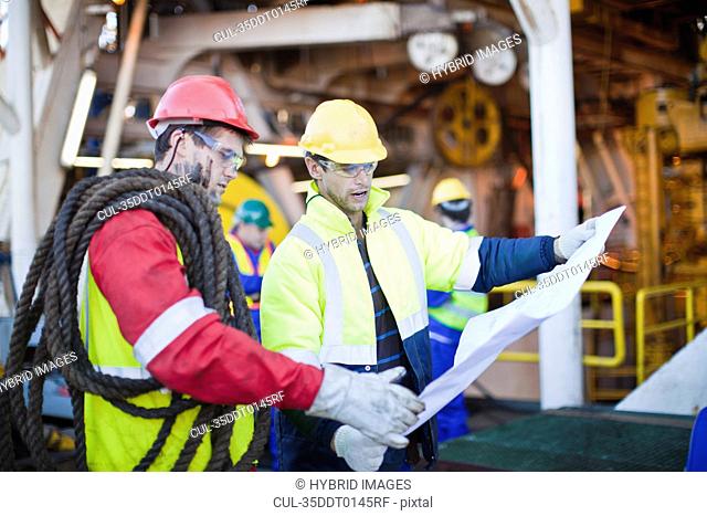 Workers examining blueprints on oil rig