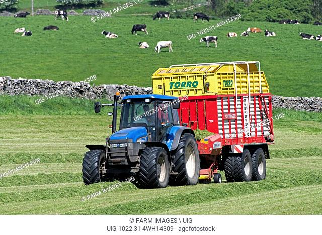 New Holland tractor towing a Pottinger forage wagon collecting grass to make silage