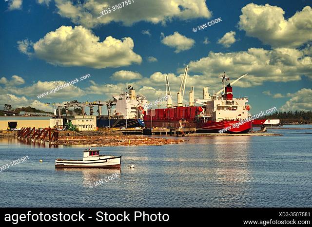 small fishing. boat and deep sea freighter loading wood products at Crofton, Vancouver Island, British Columbia, Canada
