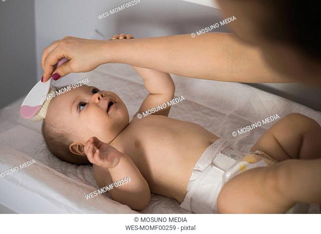 Mother brushing hair of baby girl