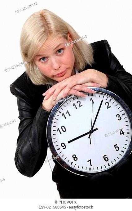 Blond businesswoman leaning on large clock