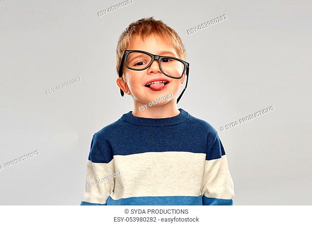 portrait of little boy in glasses showing tongue