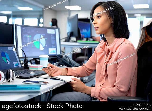 Businesswoman taking notes while sitting on her desk at modern office