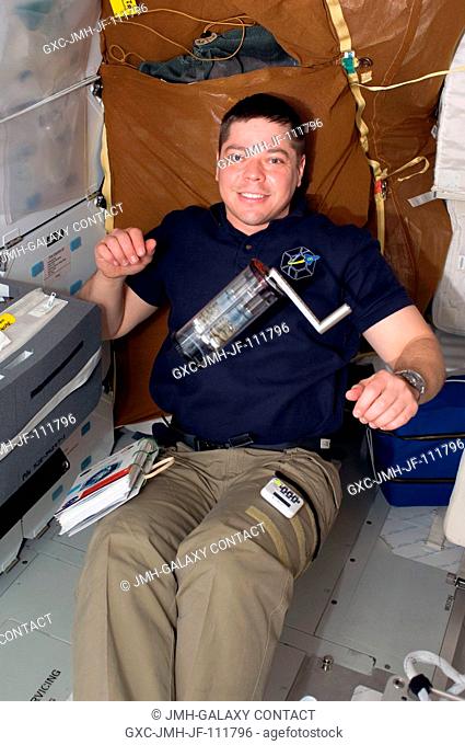 Astronaut Robert Behnken, STS-130 mission specialist, works with a Fluid Processing Apparatus, which is part of the Microbe Group Activation Pack