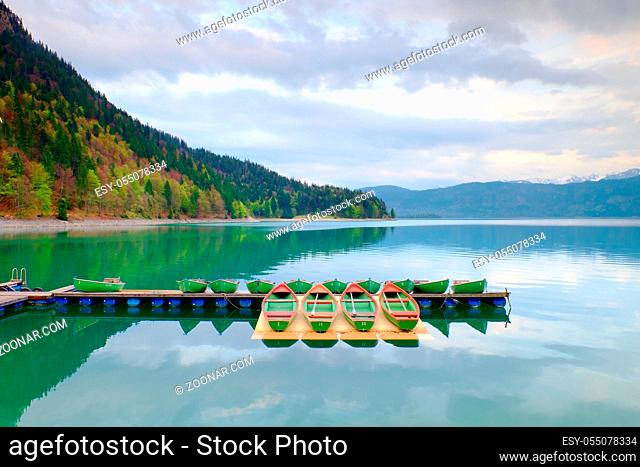 Blue Alps lake with Rental rowing boats in marina. Wharf for trip ships