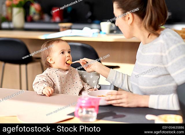 happy mother feeding baby with puree at home