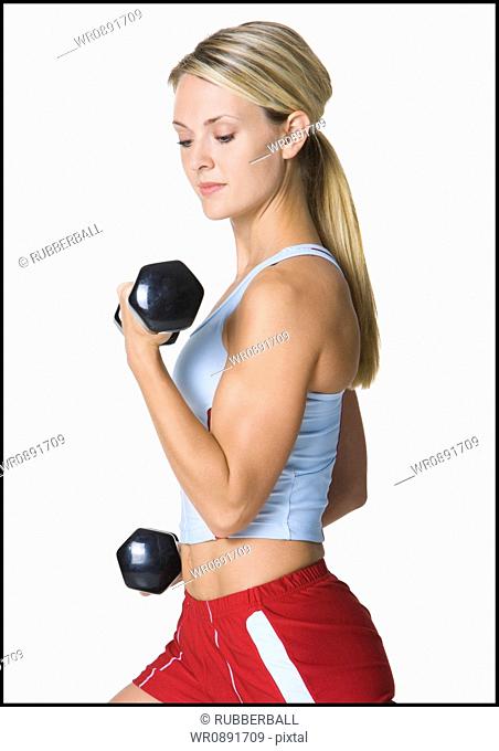 Profile of a young woman exercising with dumbbells