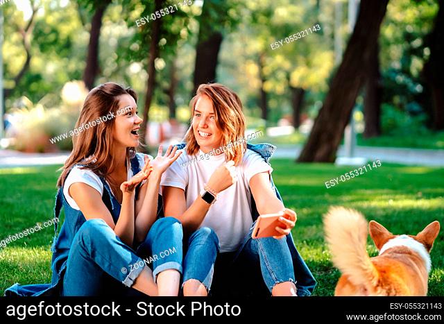 Candid friends seated at the park talking to each other. Girlfriends speaking in conversation outdoors