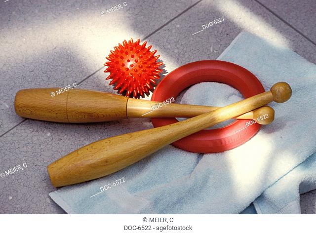 two Holzkeulen, ein red throwing ring a red massage ball on white towel
