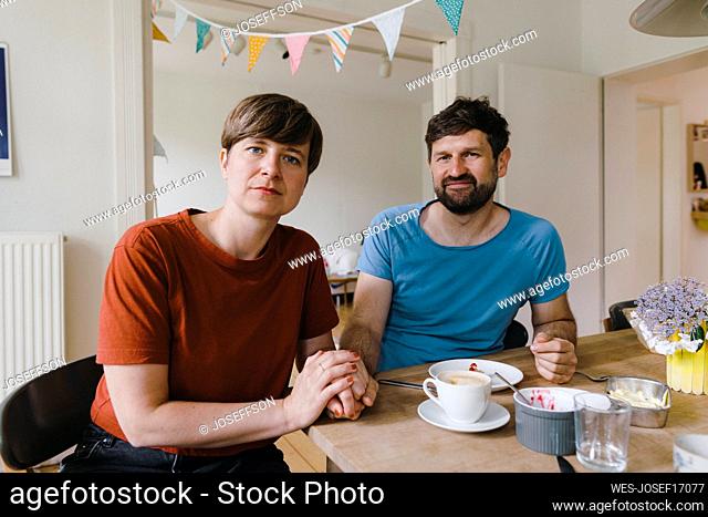 Mature couple sitting with breakfast on dining table at home