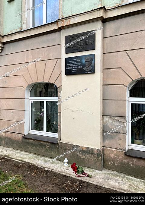 04 January 2023, Latvia, Riga: Flowers and a candle lie at the birthplace of Dietrich Loeber (1923-2004), where memorial plaques for him and his father August...