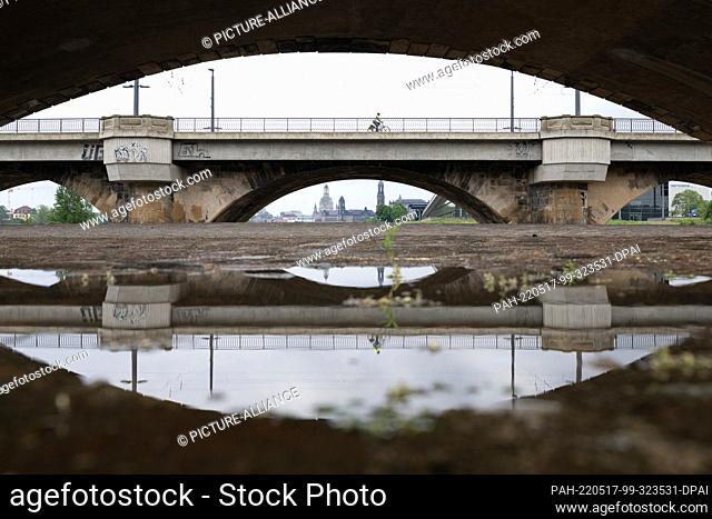 17 May 2022, Saxony, Dresden: The backdrop of the old town is reflected in a puddle below the Marienbrücke. Photo: Sebastian Kahnert/dpa