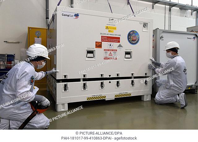 17 October 2018, Bremen: Two employees of the German Aerospace Center (DLR) pack the research satellite ""Eu:CROPIS"". The DLR satellite is to orbit the earth...
