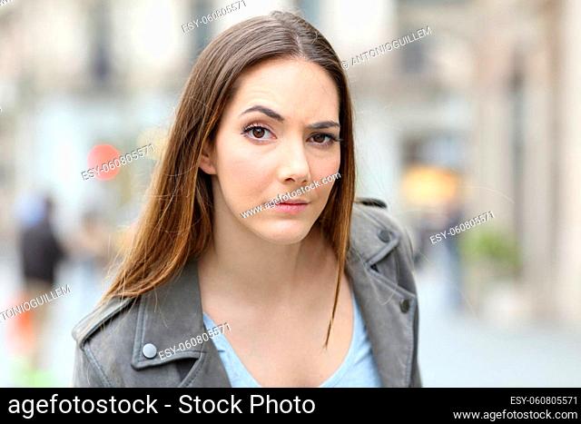 Portrait of a suspicious young woman looking at camera on city street