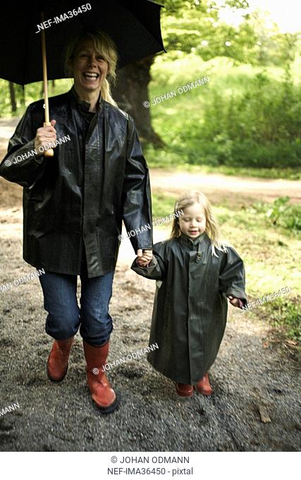 Mother and daughter in rain clothes with an umbrella