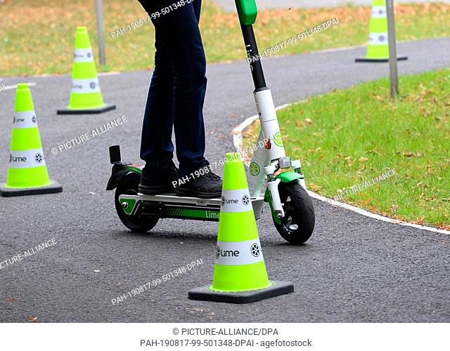 17 August 2019, North Rhine-Westphalia, Cologne: A young woman drives between green traffic caps on the youth traffic square during the e-scooter driving safety...