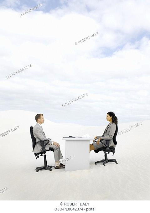 Two businesspeople in the middle of nowhere at a desk