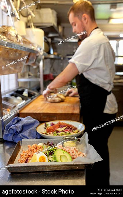 Food in restaurant kitchen, chef on background