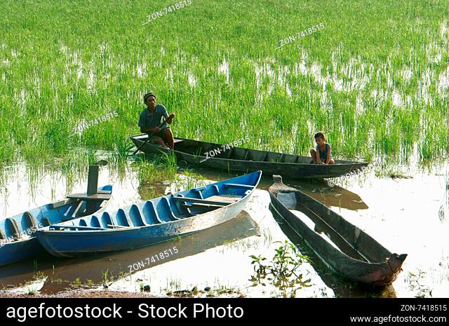 DAK LAK- VIET NAM- JUNE11: Group of Asian farmer go to work by row boat on Lak lake in summertime, family of ethnic minority, grass on lake