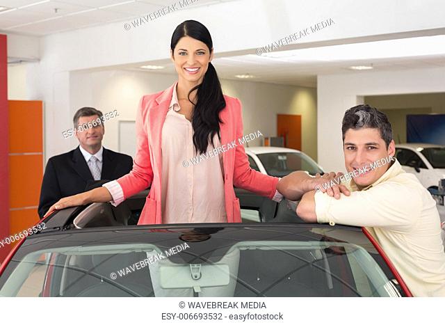 Cheerful woman standing in red cabriolet