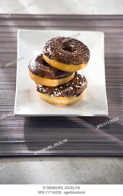 Three doughnuts with chocolate glaze and chocolate sprinkles