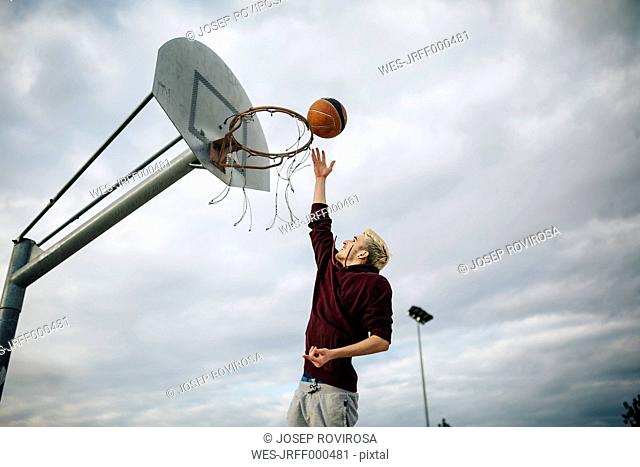 Young man playing basketball on an outdoor court