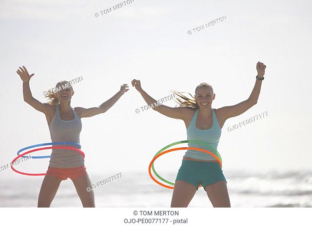 Women playing with plastic hoops on beach