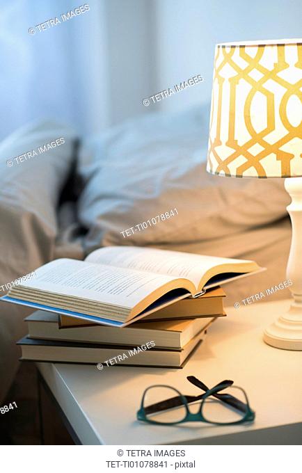 Bed with lamp, books and glasses on bedside table